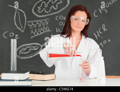 Focused young scientist pouring a liquid in a gratuated cylindre Stock Photo