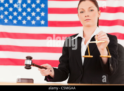 Close up of a cute judge knocking a gavel and holding scales of justice Stock Photo