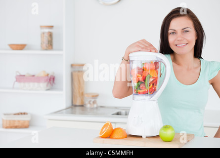 Dark-haired woman posing with a blender Stock Photo