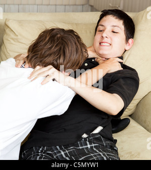 Two brothers playfully fighting on the couch.  Stock Photo