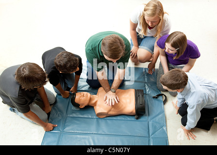 Group of teenagers learing CPR (cardiopulmonary resuscitation) in school.  Stock Photo