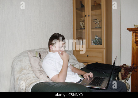 image of teenage boy on laptop in house Stock Photo