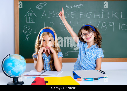 clever nerd student girl in classroom raising hand with sad friend Stock Photo