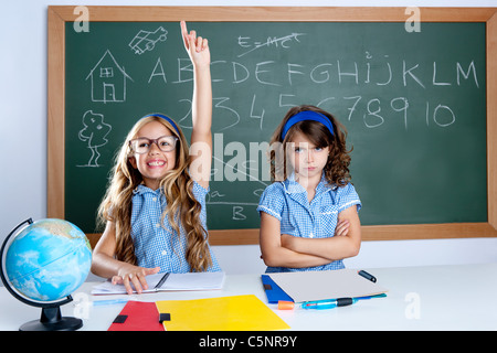 clever nerd student girl in classroom raising hand with sad friend Stock Photo