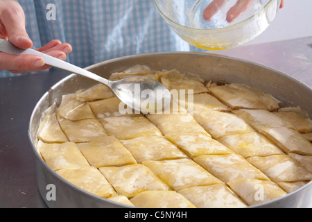 Baklava: spreading top of cake with hot butter Stock Photo