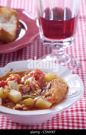 Basque fish soup wot a glass of red wine behind Stock Photo