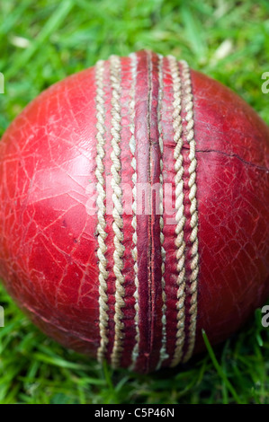 red cricket ball on green grass,CRICKET, BALL, RED, SEAM, OLD, WORN, DISTRESSED, SPIN, seam, english summer, grass, Dave Podmore Stock Photo