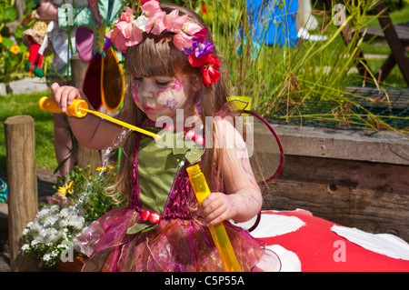 Little Girl Dressed In Fancy Dress Blowing Bubbles Stock Photo