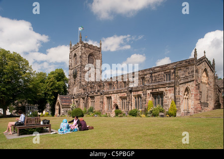 Holy Trinity Church, Skipton - friends & family sitting, relaxing on sunny scenic churchyard garden lawn under blue sky (North Yorkshire, England, UK) Stock Photo