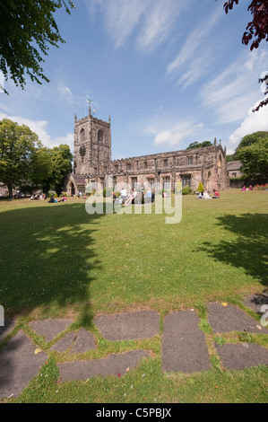 Holy Trinity Church, Skipton - friends & family sitting, relaxing on sunny scenic churchyard garden lawn under blue sky (North Yorkshire, England, UK) Stock Photo