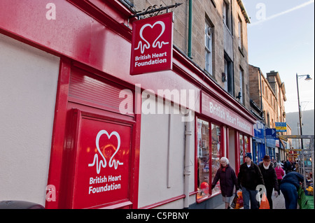 Busy high street on market day (people carrying shopping bags, shops & British Heart Foundation charity shop logo - Otley, West Yorkshire, England. Stock Photo