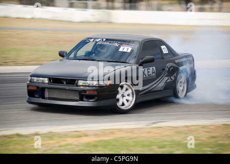 Nissan S13 Japanese sports car being used in drift motorsport, sliding and tire spinning through a corner Stock Photo