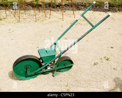 Old fashioned mechanical seed drill hand pushed to control even placing of seeds Stock Photo