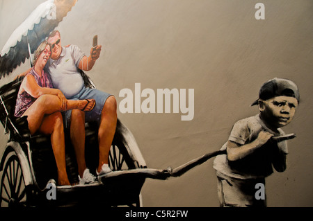 Banksy picture of small third world boy pulling 2 large Western tourists in a rickshaw Stock Photo