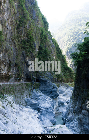 Cliffside road under rock overhang and stream flowing through marble canyons, Tunnel of Nine Turns, Taroko National Park, Hualien, Taiwan Stock Photo