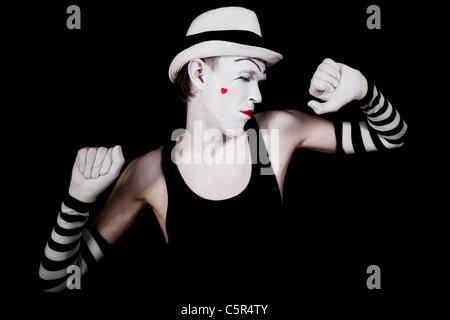 Portrait of a dancing mime in white hat with a heart on her cheek on black background Stock Photo