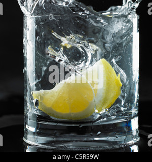 Lemon dropped into glass of water Stock Photo