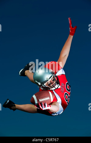 American Footballer flying through the air to make the catch. Stock Photo