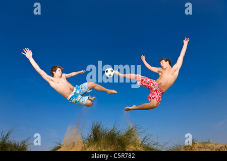 Two players playing beach soccer compete for the ball. Stock Photo