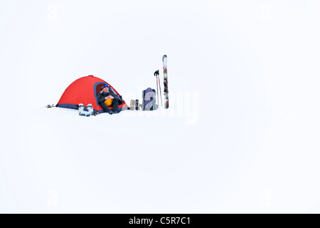 A women trying to keep warm sitting in her tent on mountain snow. Stock Photo