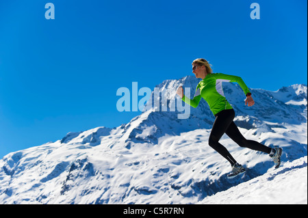 A woman jogging in high snowy alpine mountains. Stock Photo