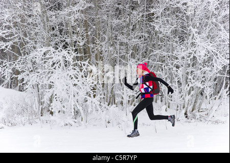 A jogger running quickly through a winter forest. Stock Photo