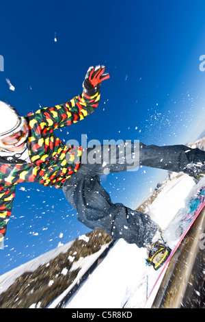 Snowboarder sliding rail in snow park.