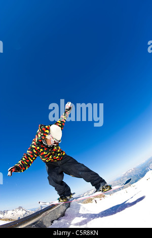 A snowboarder slides a rail in a snow park