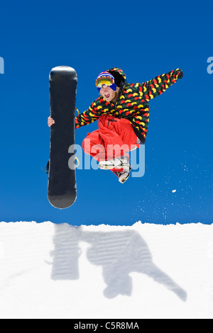 A snowboarder leaps from the side of a half pipe in celebration. Stock Photo
