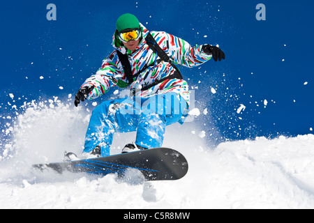 A snowboarder riding hard through off piste snow. Stock Photo