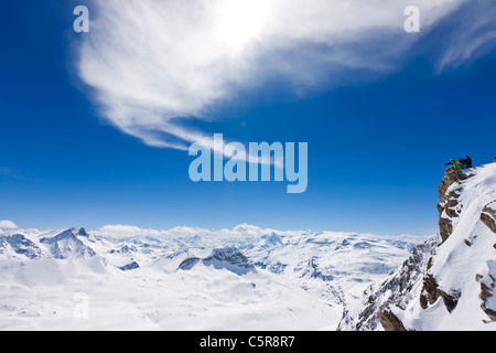 Three snowboarders look out over snowy mountain range, Stock Photo