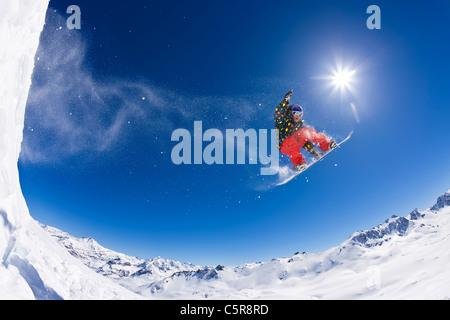 A snowboarder flying over snow covered peaks. Stock Photo