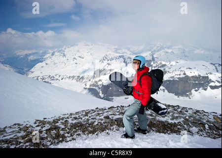 A snowboarder looks out over stunning snowy mountains Stock Photo