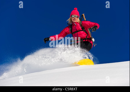 A snowboarder rides deep fresh powder snow at speed. Stock Photo