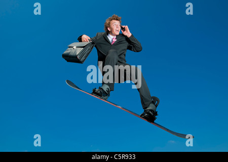 A snowboarding businessman on cell phone. Stock Photo