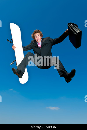 A businessman is happy to get away on his snowboarding vacation. Stock Photo