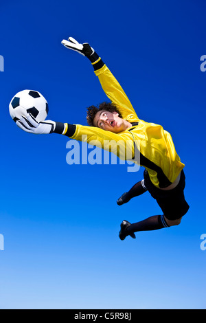 A goalkeeper gets a hand to the ball to make the save. Stock Photo