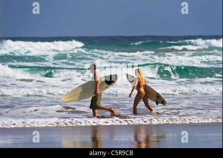 Two surfers heading out to the ocean waves. Stock Photo