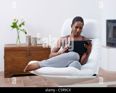 mid adult indian woman relaxing on armchair and using touch pad computer. Horizontal shape, front view, copy space Stock Photo