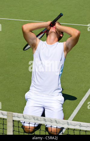 A tennis player drops after losing the game. Stock Photo