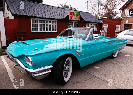 A 1965 pale blue Ford Thunderbird convertible with a mature couple driving in it Stock Photo