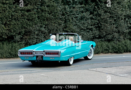 A 1965 pale blue Ford Thunderbird convertible with a mature couple driving in it Stock Photo