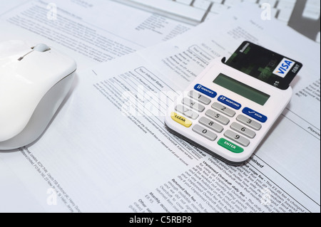 Internet Bank Card Reader with Card Inserted Sitting on Bank Statements with Other Credit Cards and Keyboard in the Background Stock Photo