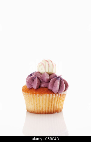 Close up of buttercream black currant cupcake with chocolate truffle against white background Stock Photo