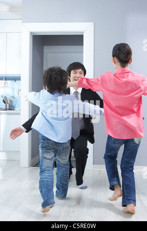 Two children greeting his father coming home Stock Photo