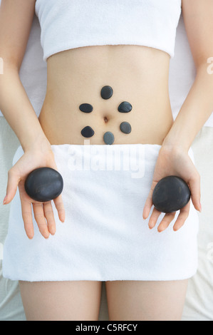 A woman getting hot stone massage therapy in the middle section Stock Photo
