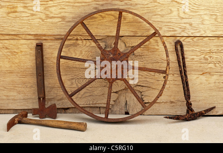 Rusty mining tools: picks, wheel, ax with worn wood background Stock Photo