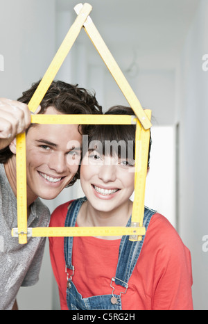 Germany, Cologne, Young couple holding house model pocket ruler in front of them Stock Photo