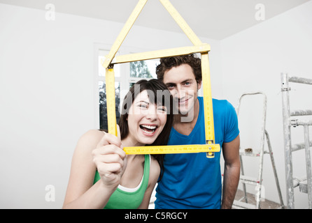 Germany, Cologne, Young couple holding house model pocket ruler in front of them Stock Photo