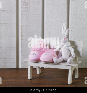 Baby's shoes and a doll on a bench figurine Stock Photo